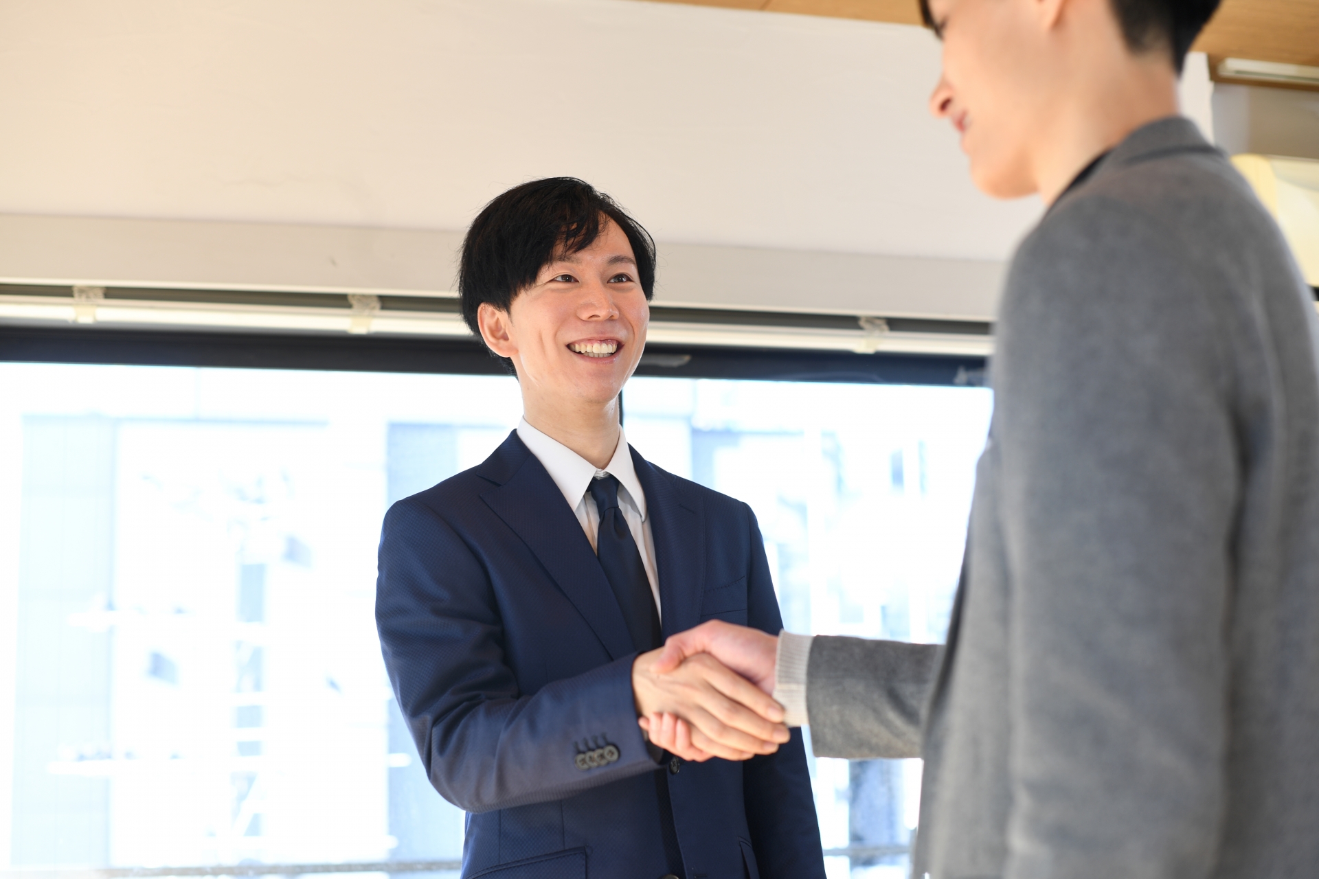 屋内で握手をするアジア人のビジネスマン達