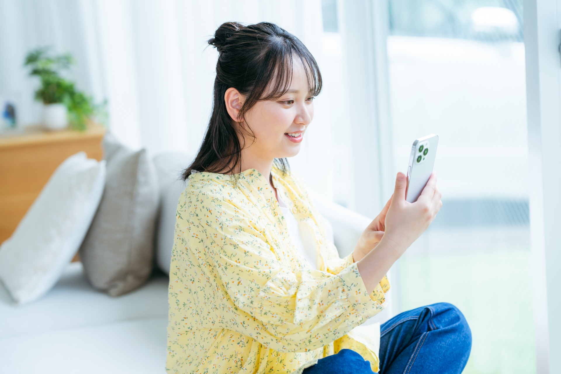 部屋でスマホを操作する若い女性