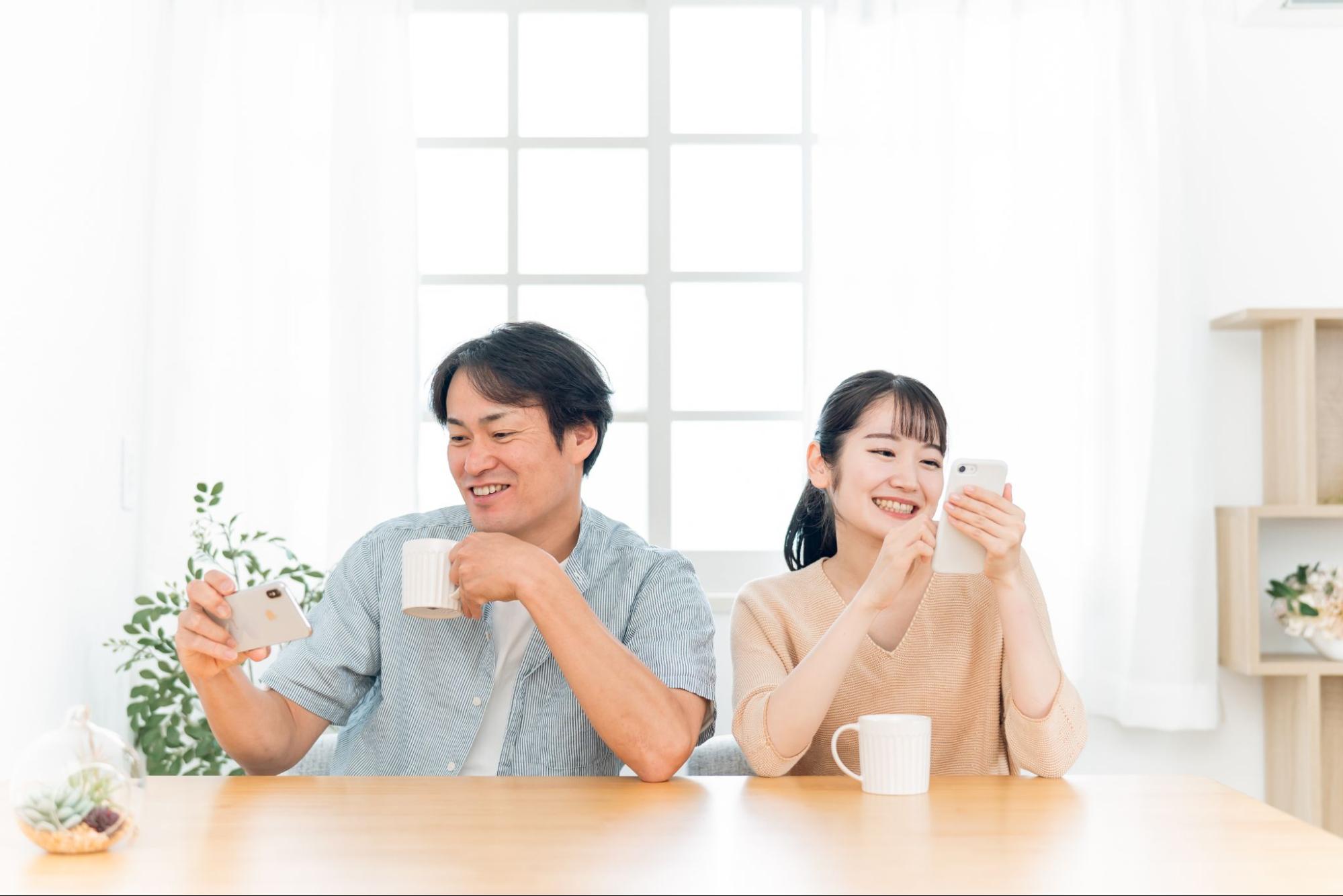 お互いにスマホを見る夫婦（笑顔）