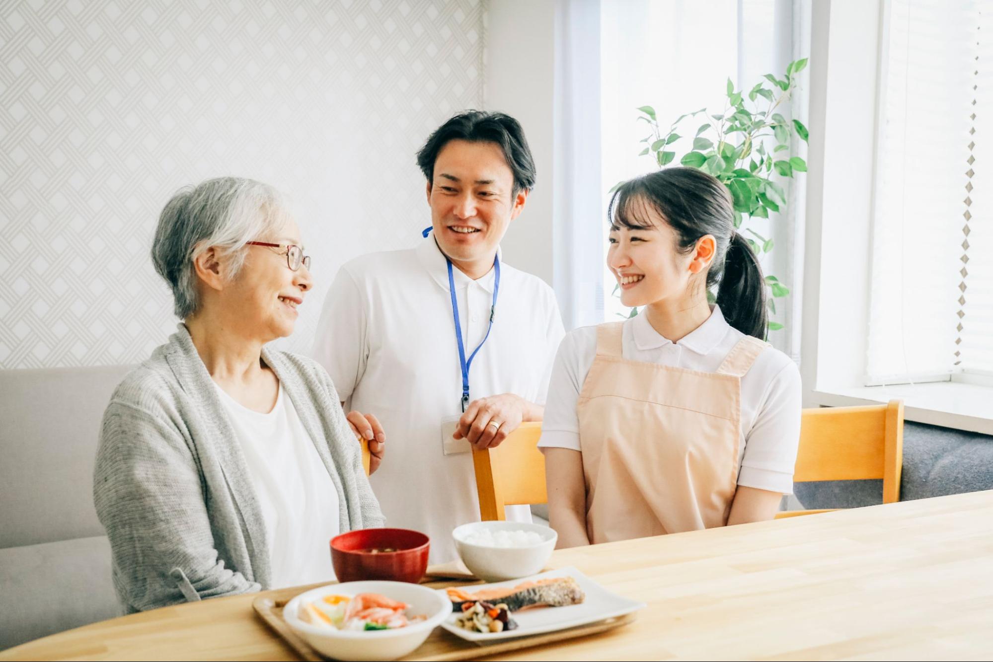 食事する高齢者と男女のスタッフ