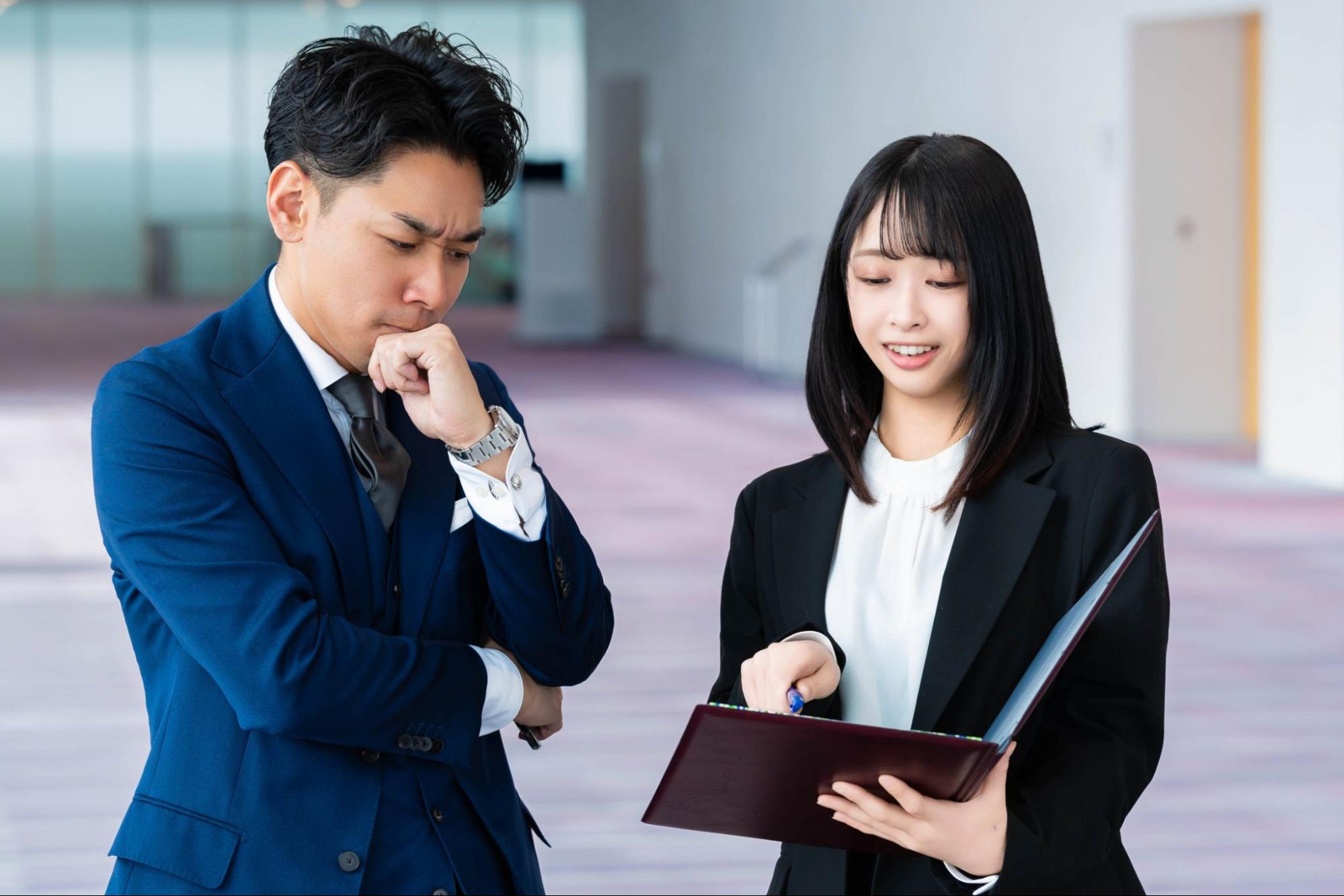 悩む上司に説明する後輩女性