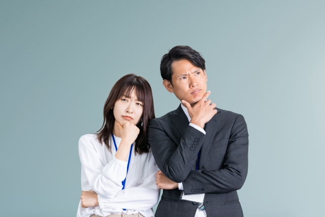 困った顔で考えるビジネスマン男女