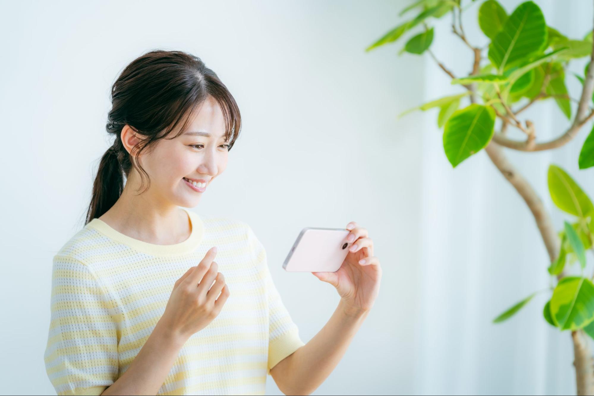 部屋でスマホを操作する女性
