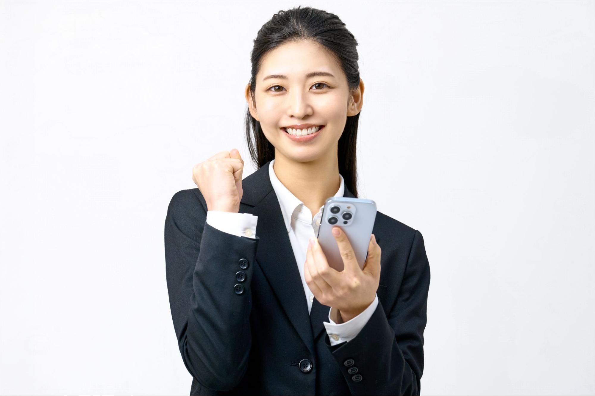 スマホを持ってガッツポーズをする女性