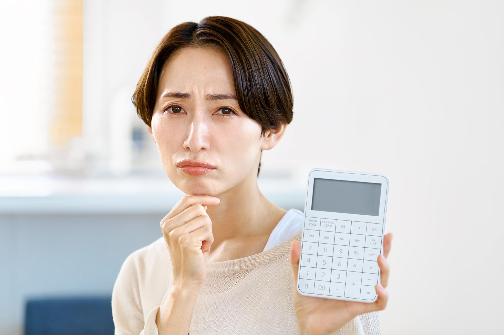 電卓を持って困る女性