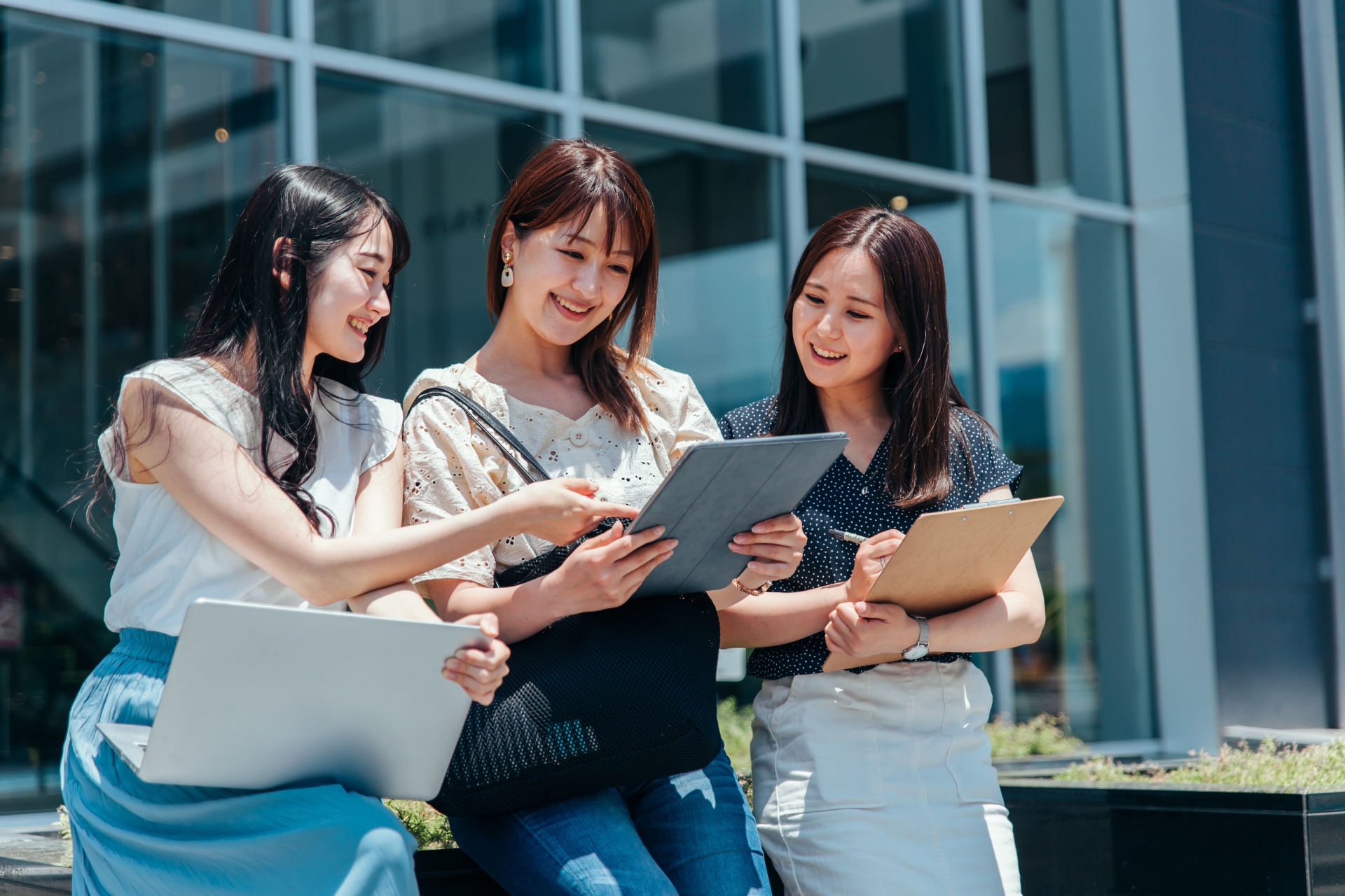 友達とキャンパスで勉強する女子大生