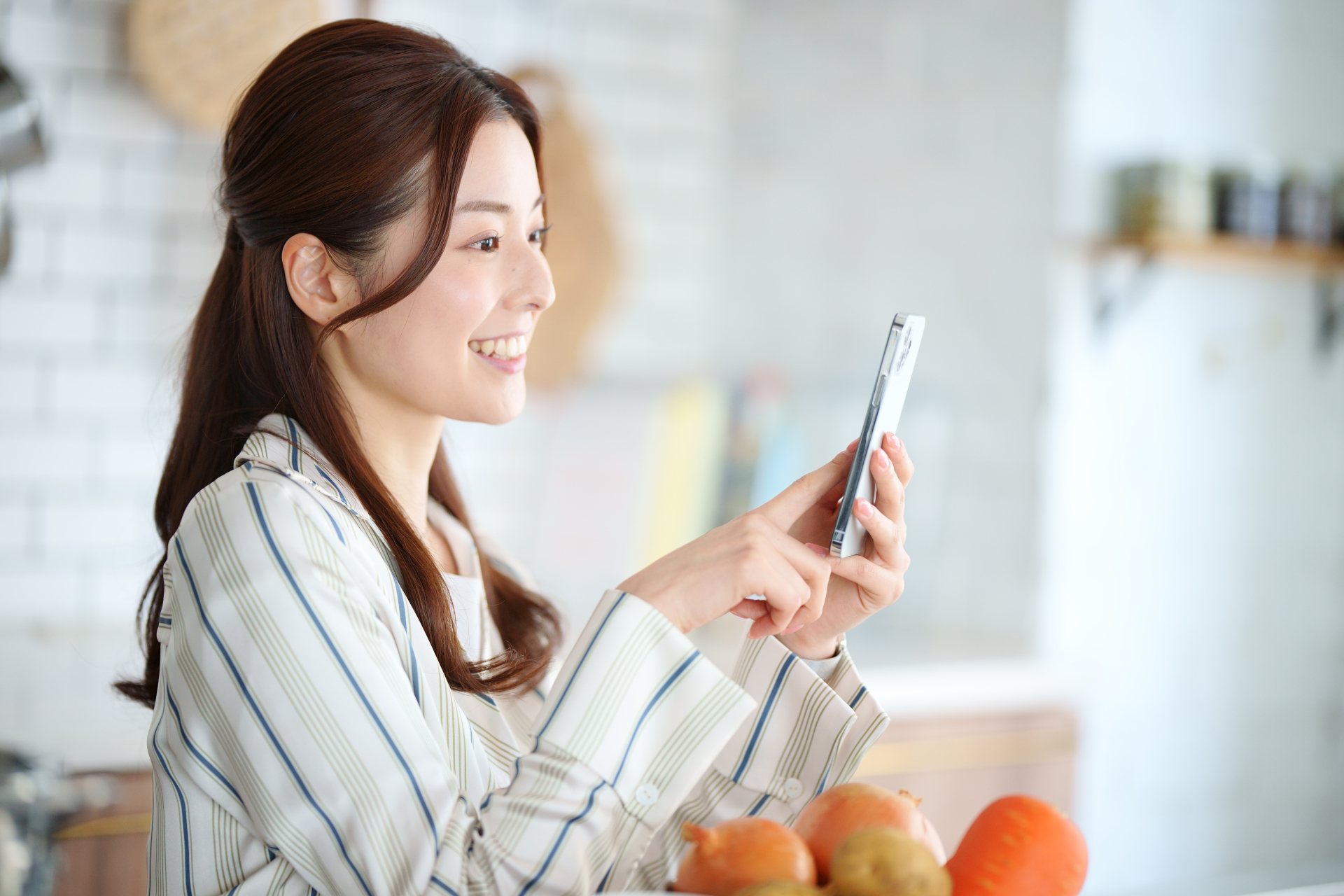 キッチンでスマートフォンを使っている横向きの女性