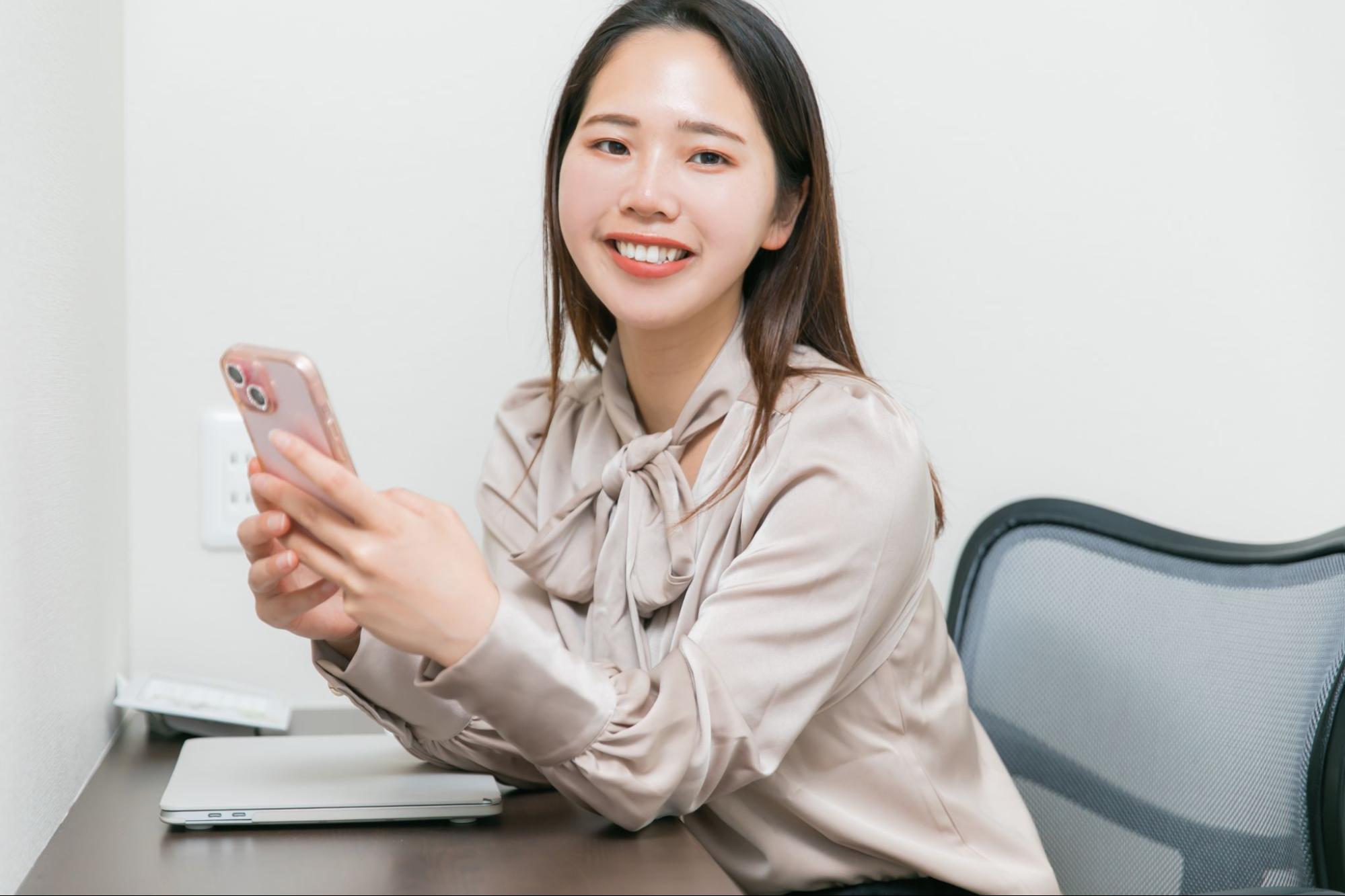 スマホを持って微笑む女性