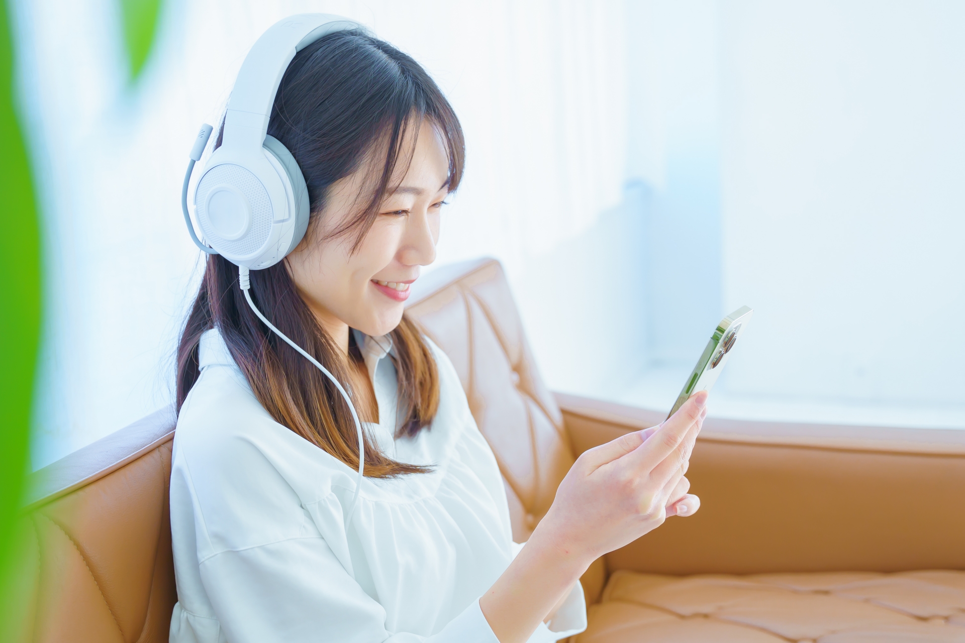 ヘッドフォンをしてスマホを見る笑顔の女性