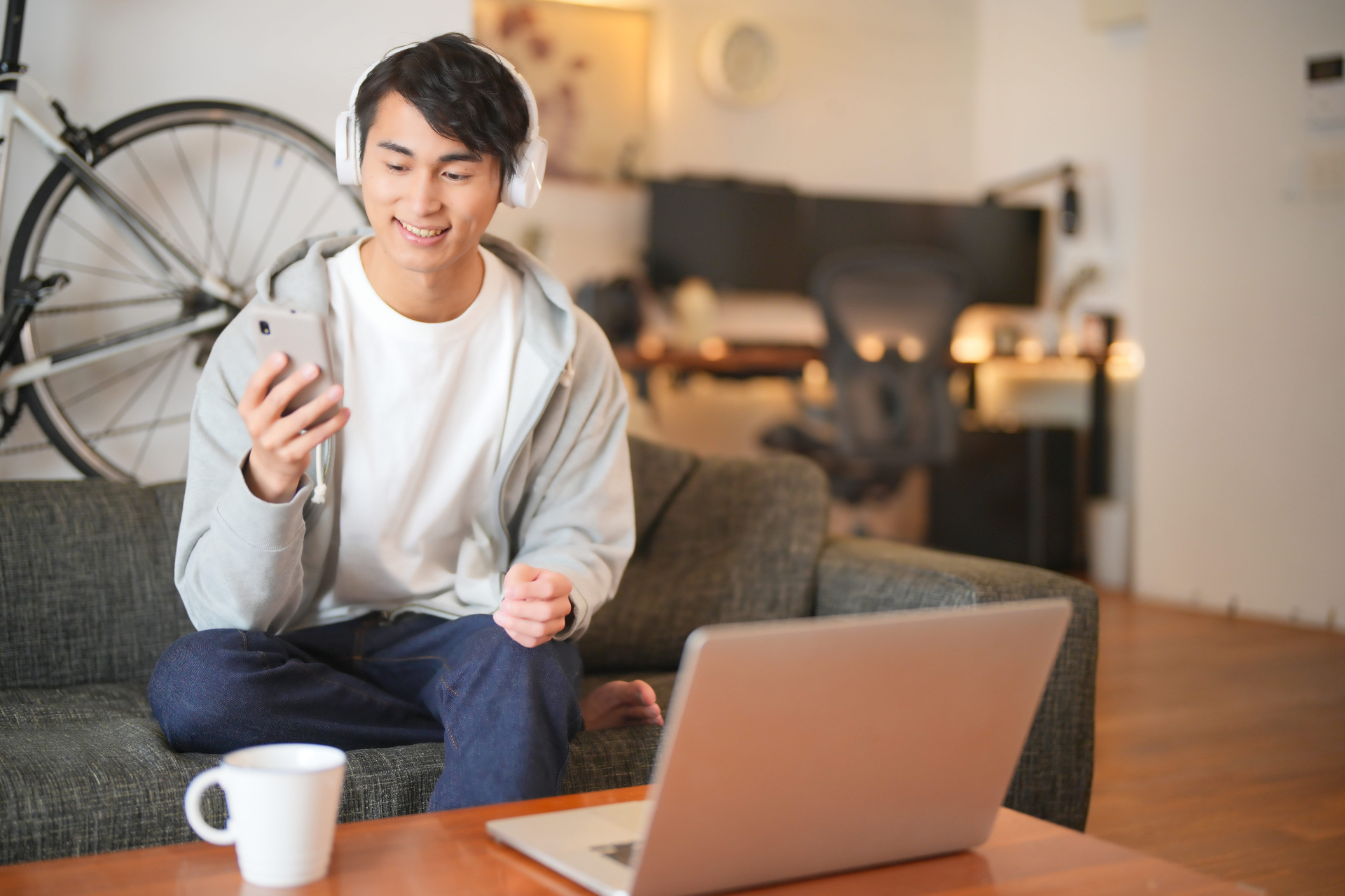ソファーに座ってノートパソコンとスマホを使う男性2