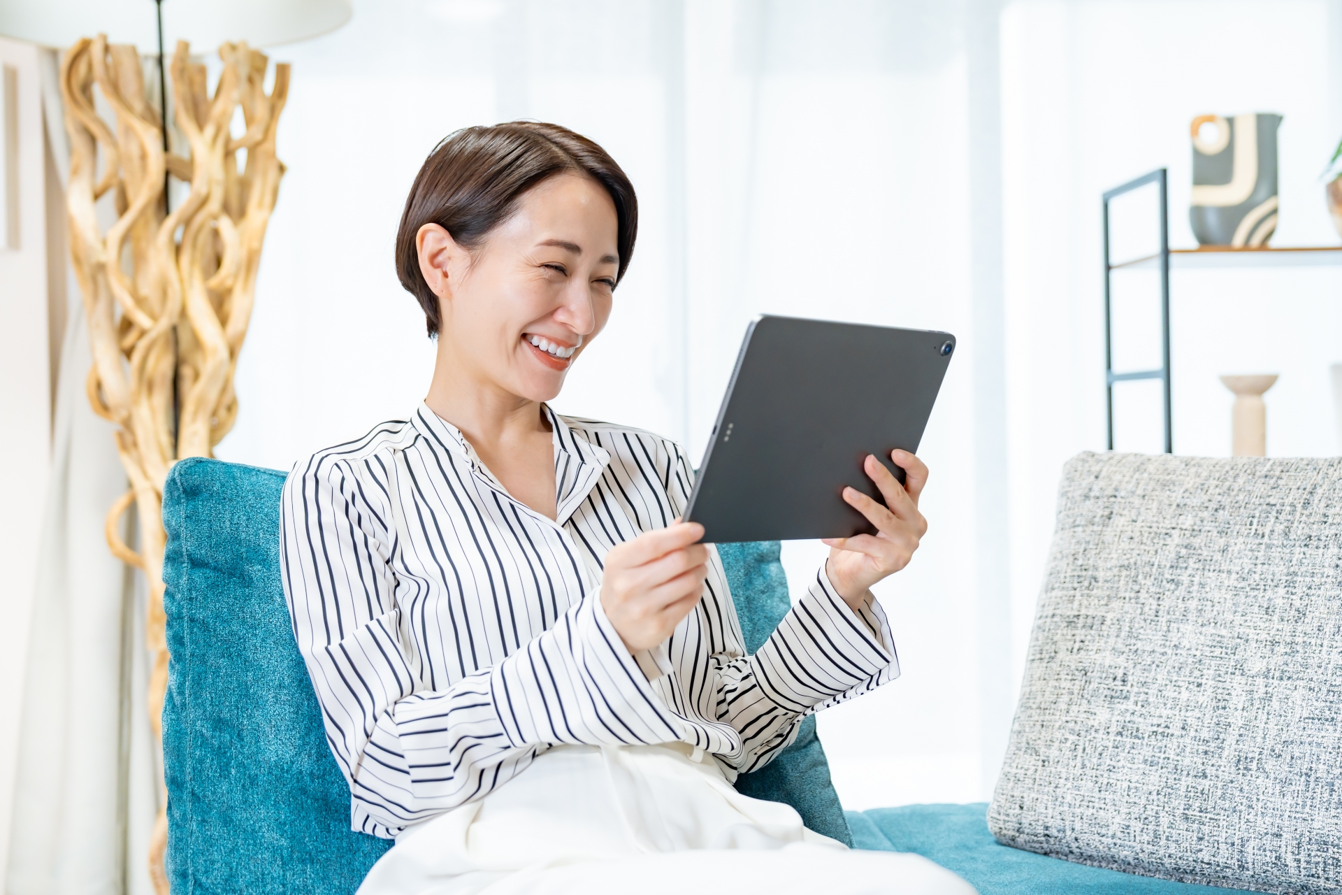 ソファに座りタブレットを見る女性