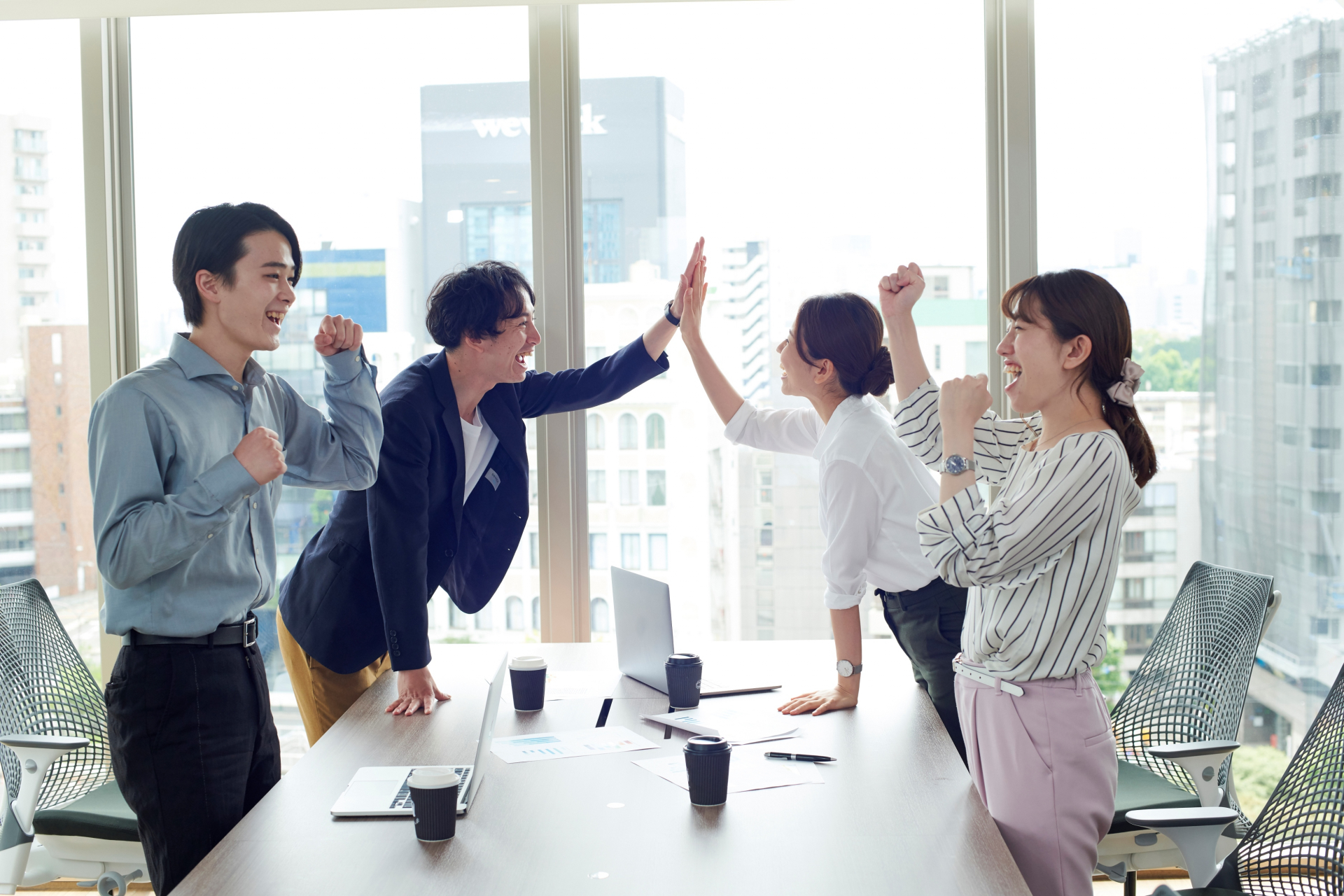 会議中にハイタッチする4人の男女