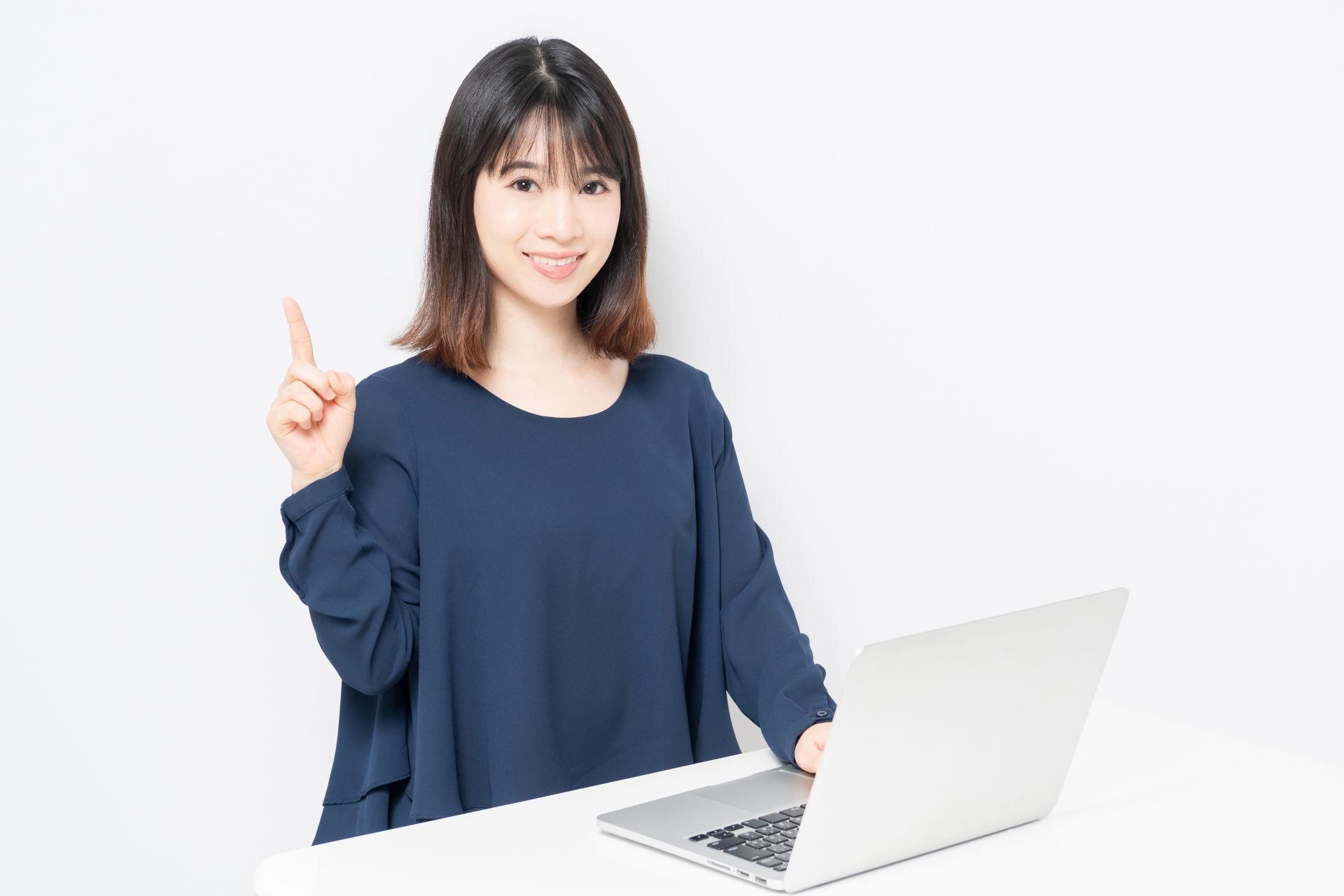 白い背景の前でノートパソコンを操作する若い女性