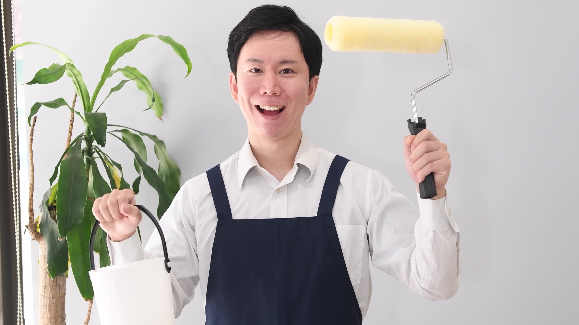 笑顔で塗装ローラーを持つエプロン姿の男性
