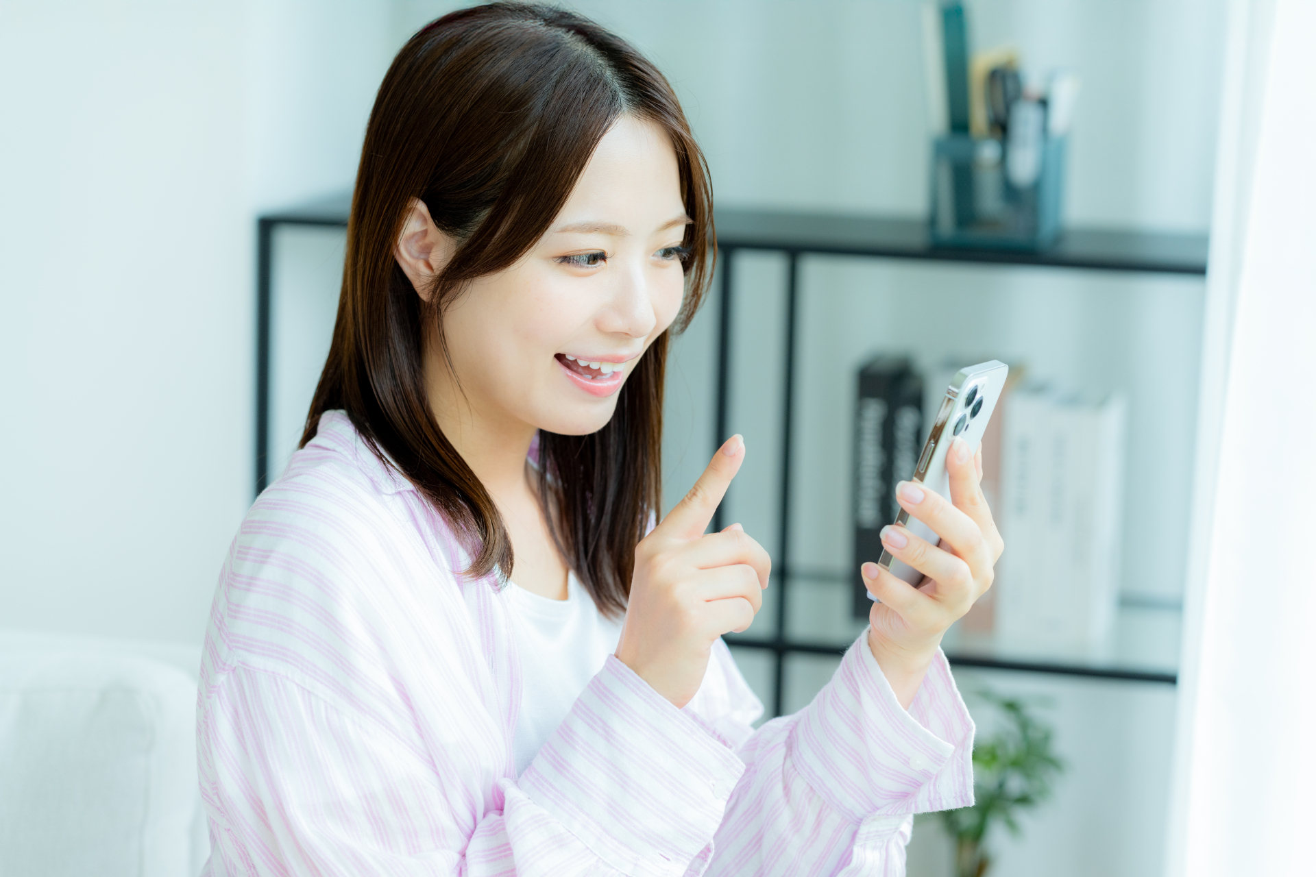 部屋でスマホを操作する若い女性