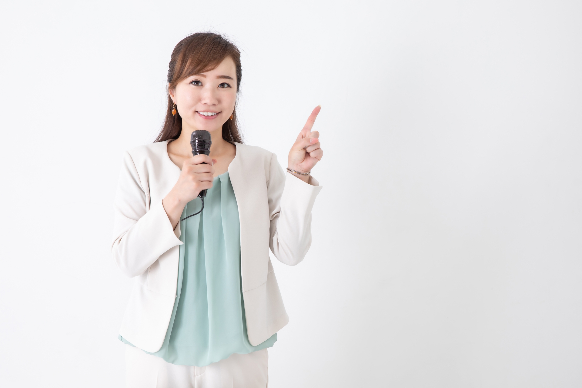 マイクを持って指を指す女性