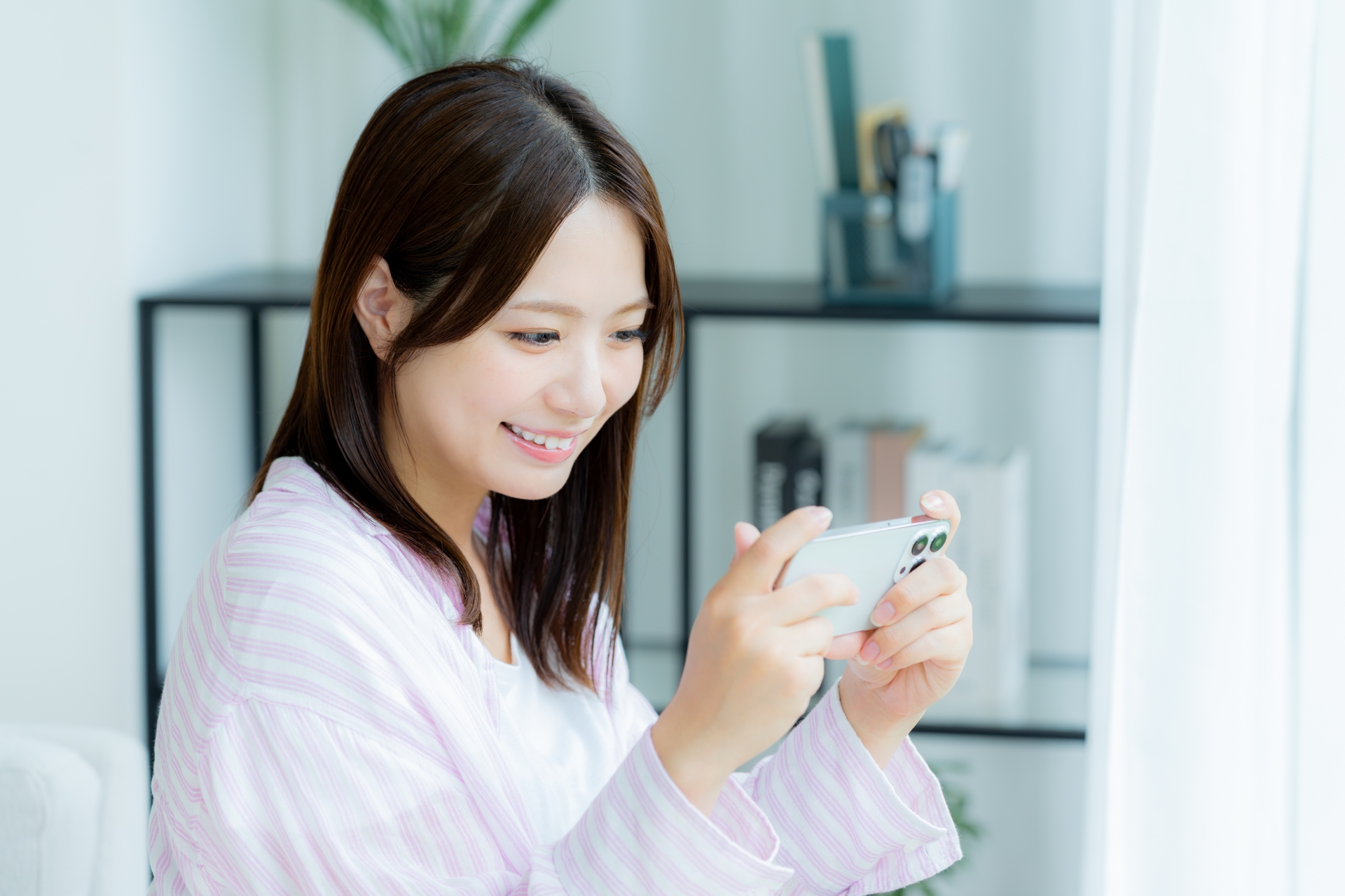 部屋でスマホを操作する若い女性