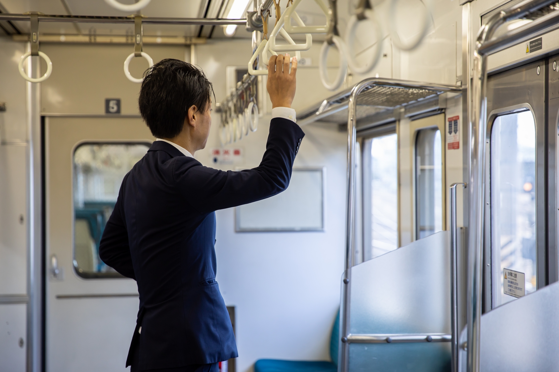 つり革につかまって電車にゆられる男性　go to work