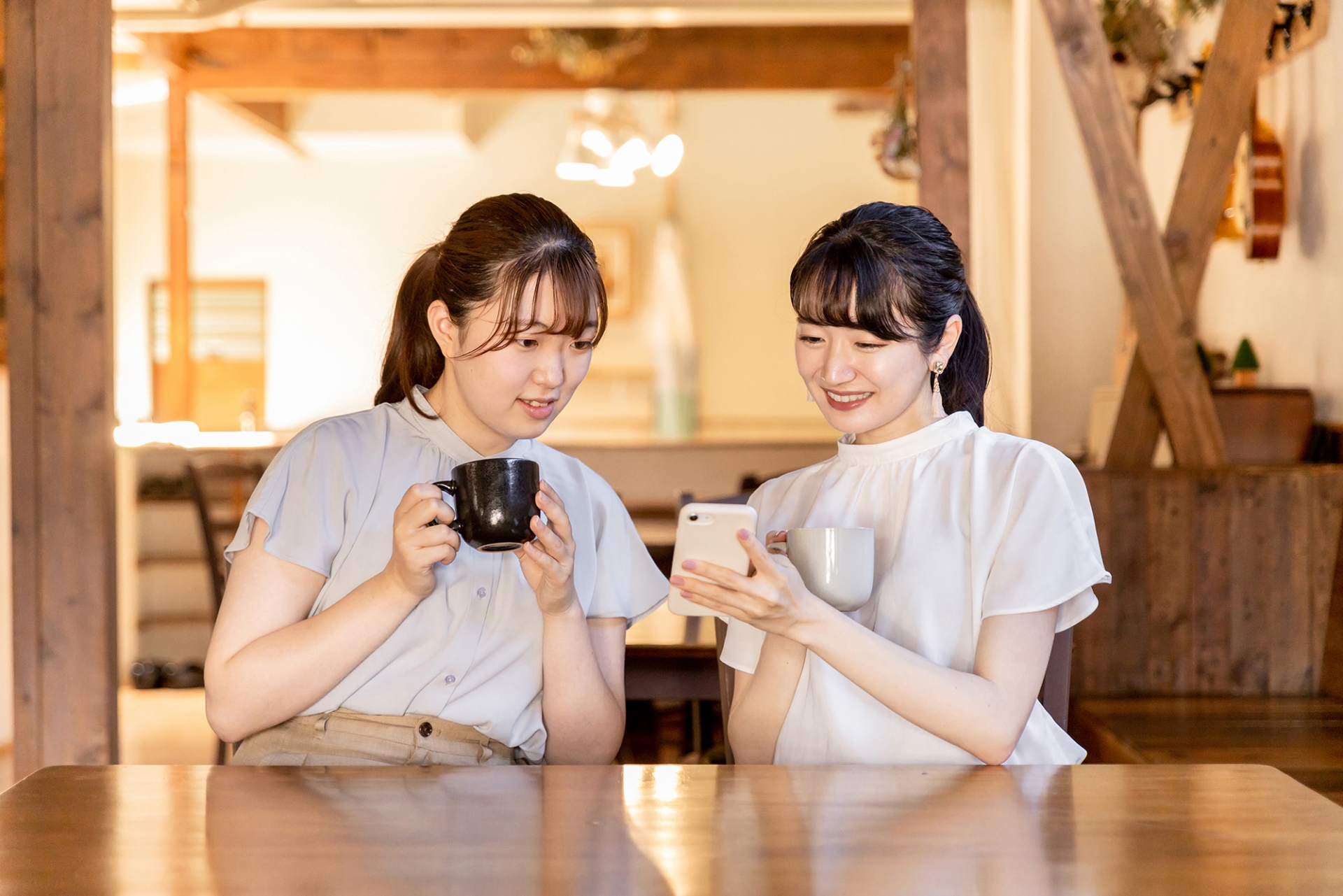 カフェでスマホを見ながら話す2人の女性