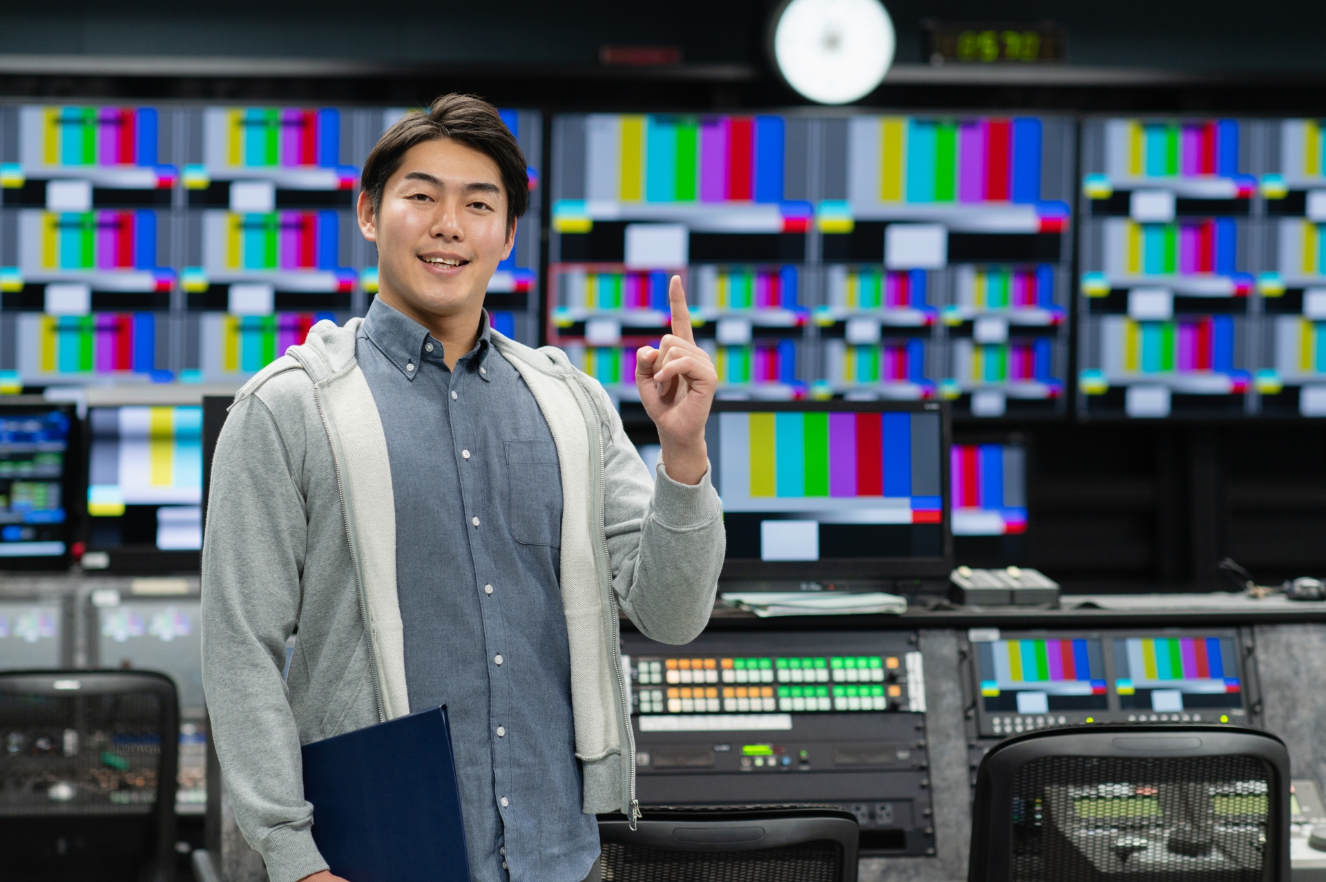 TV局で人差し指を立てている男性