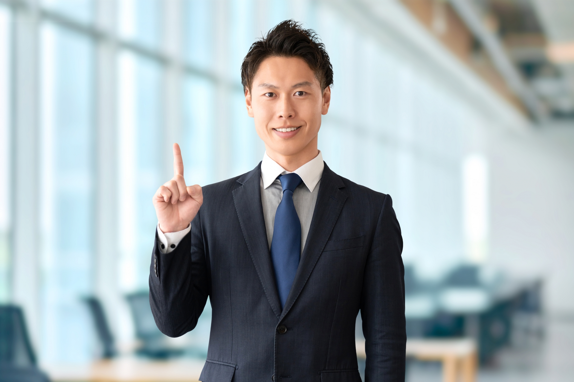 人差し指を立ててスーツを着ている男性
