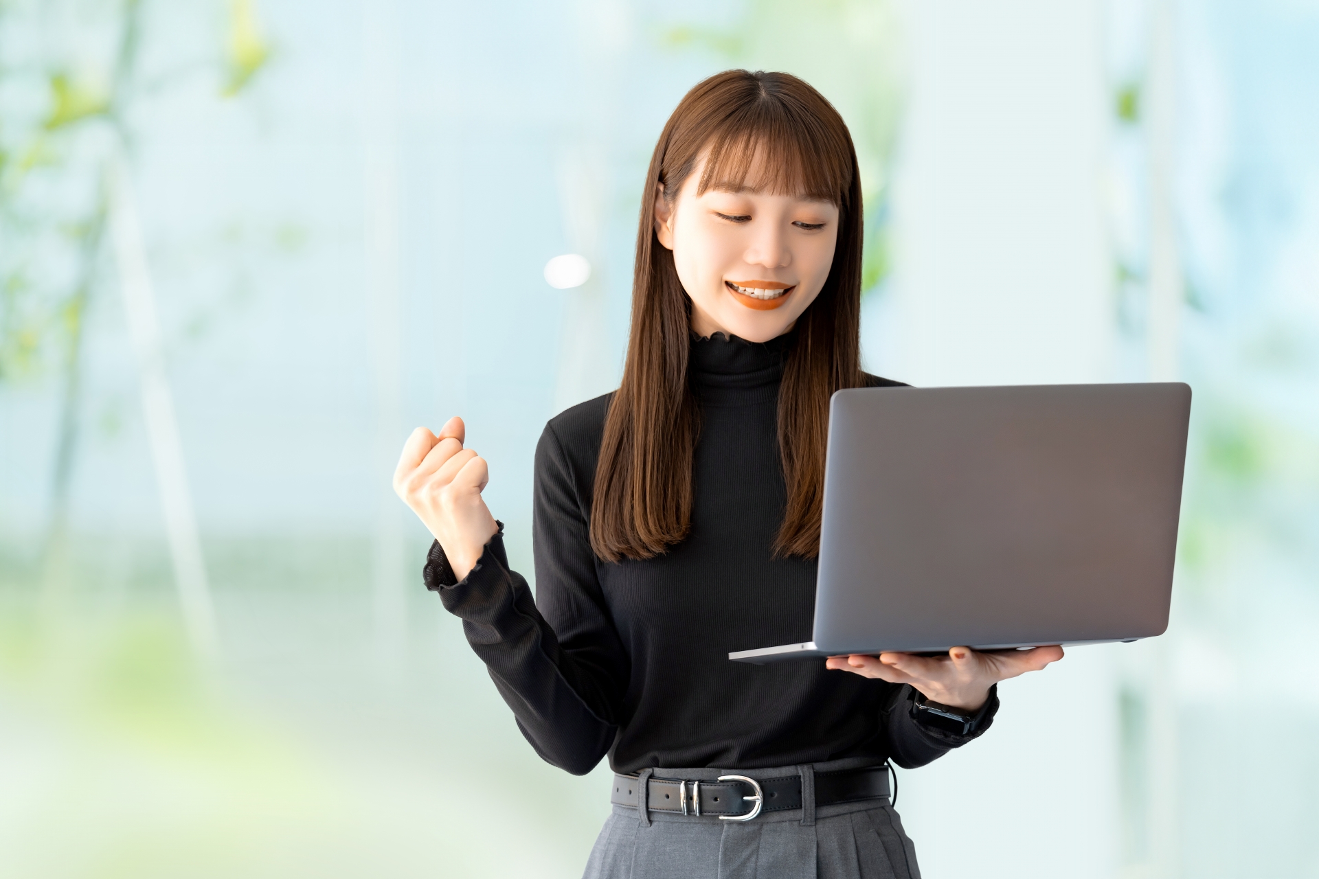 パソコンを見てガッツポーズをする女性
