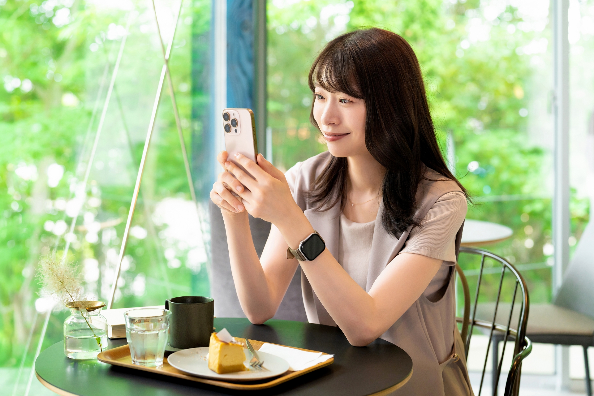 カフェでスマホを使う笑顔の女性