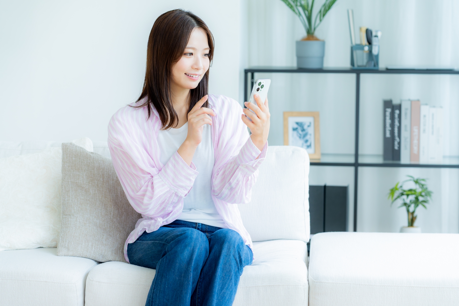 部屋でスマホを操作する若い女性