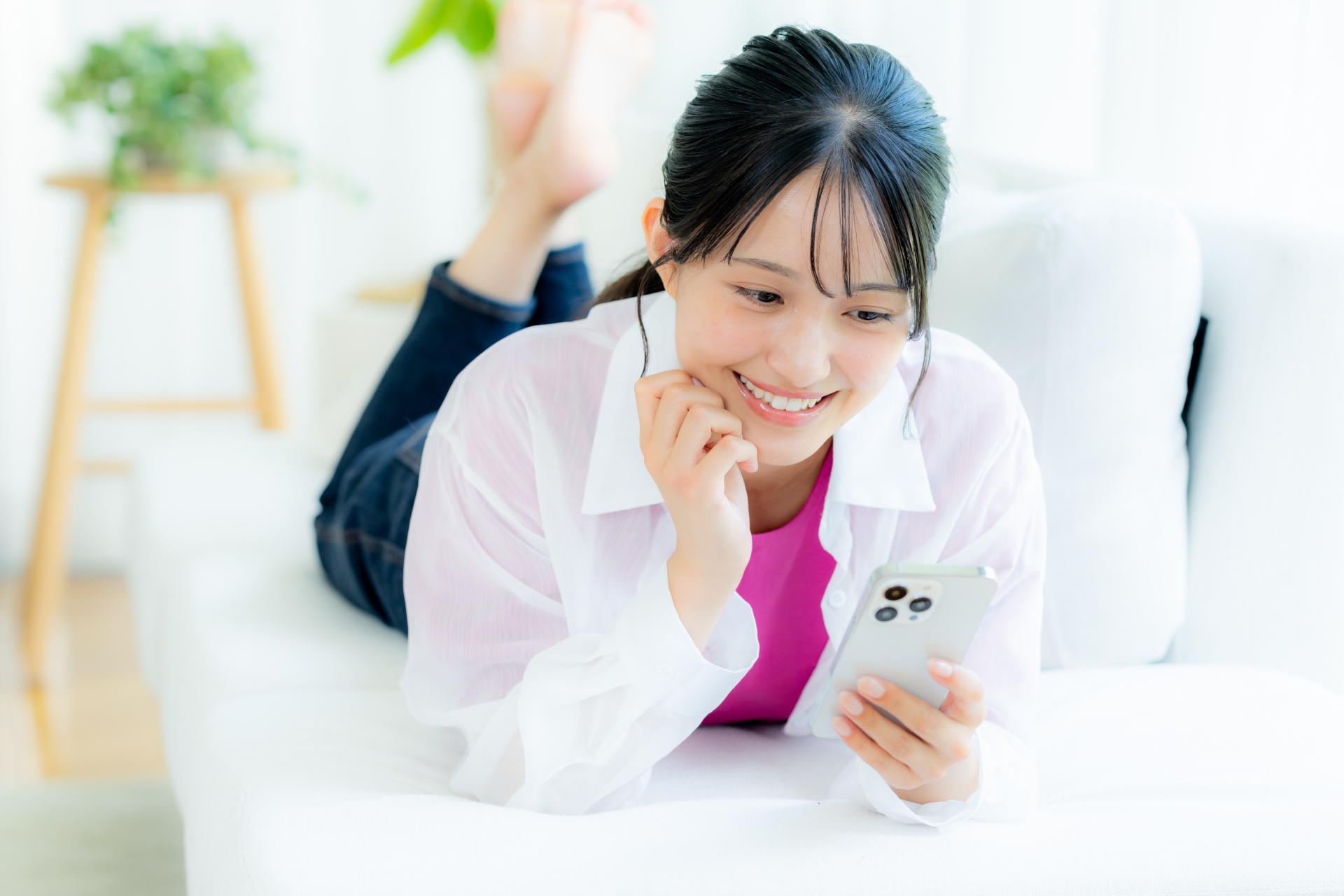部屋でスマホを操作する若い女性