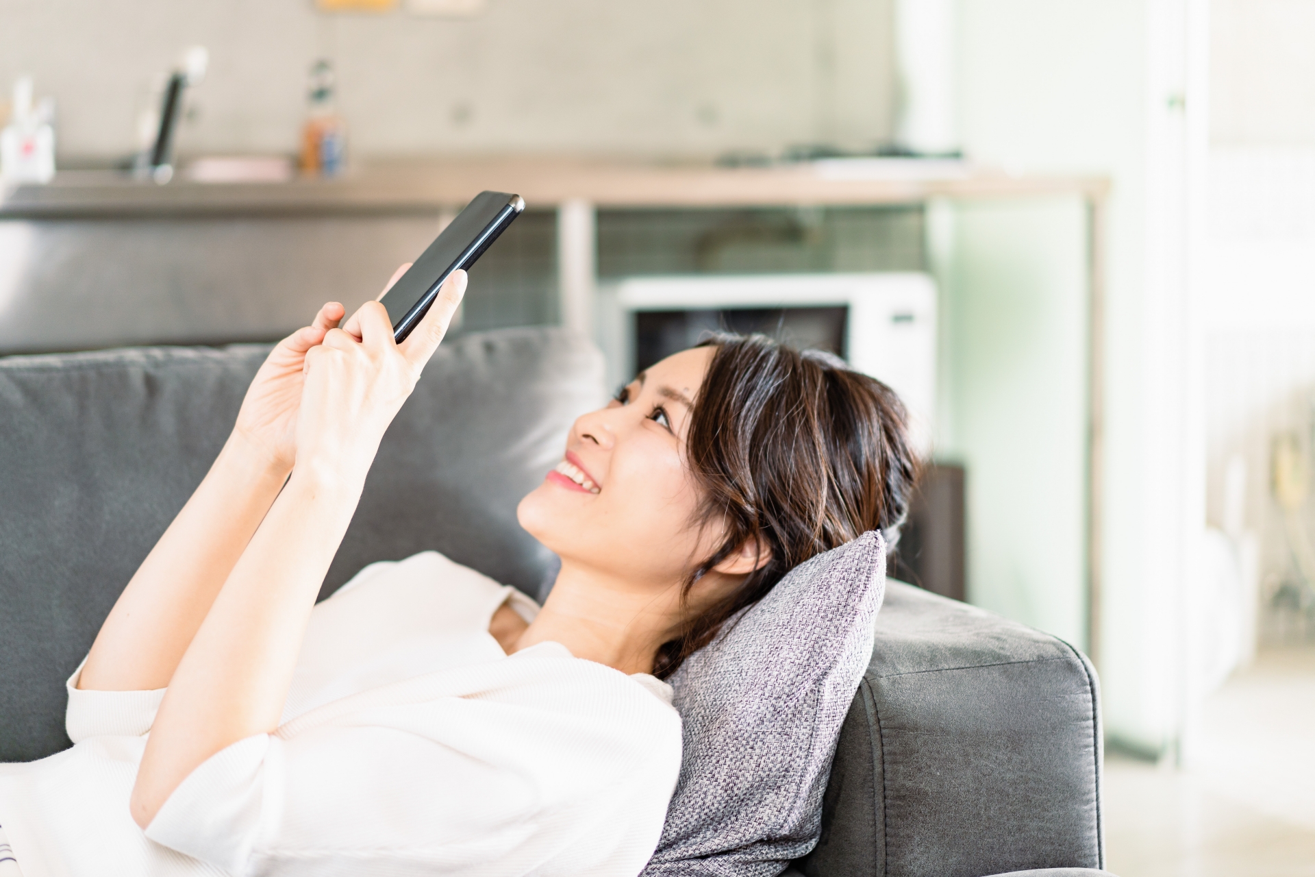 部屋でスマホを使う若い女性