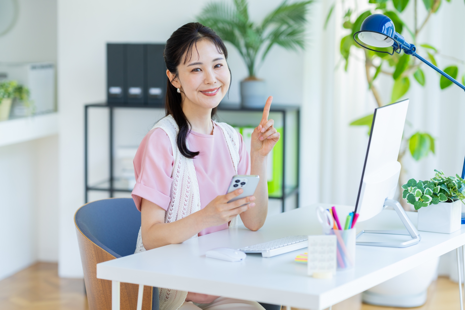 スマホを持って人差し指を立てている女性