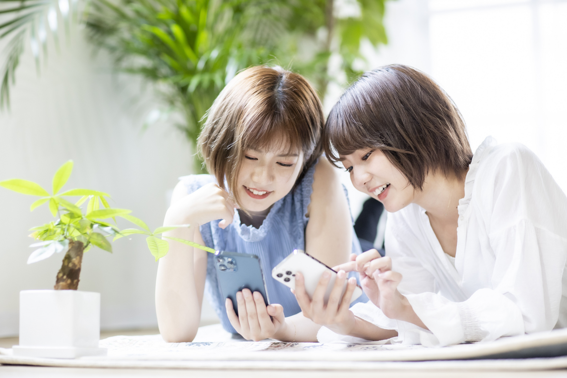 寝転んでスマホを見る女性達